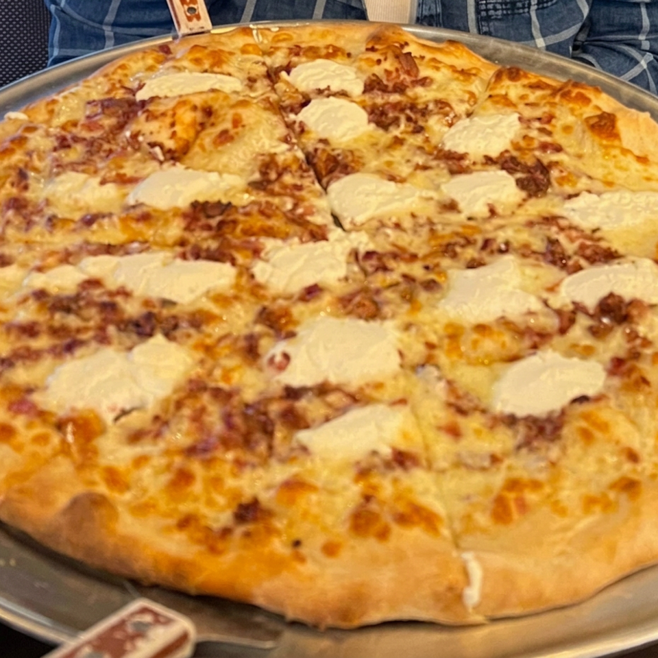 Golden-crust pizza topped with cheese on a metal serving tray.